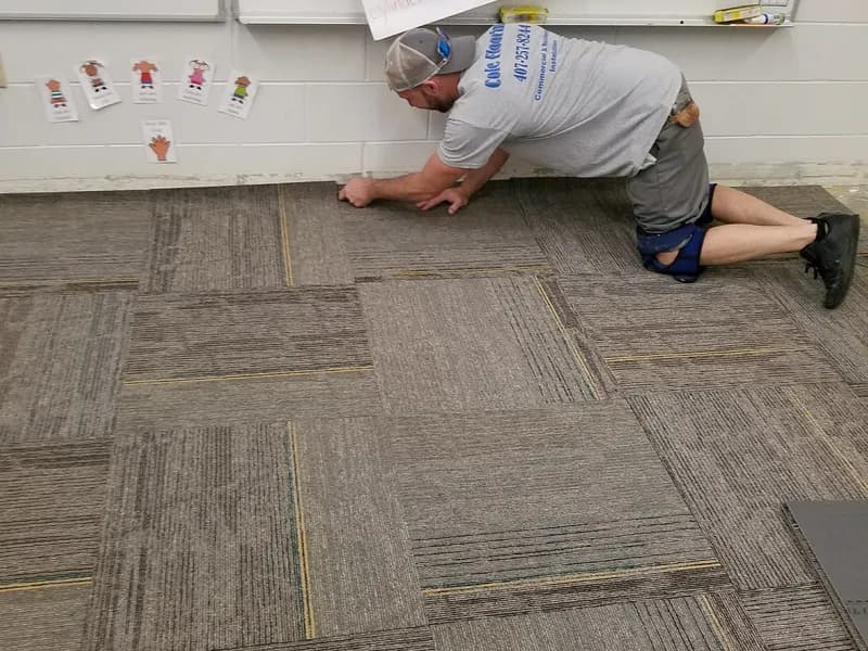 Travis installing carpet tile in a school classroom